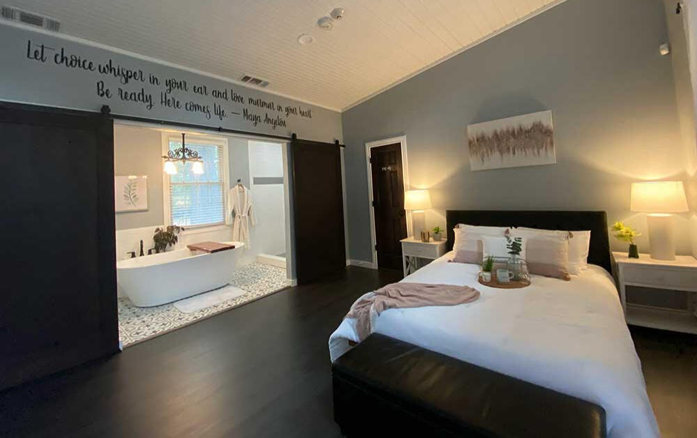 The Trinity Suite features a walk in shower and a freestanding oval-shaped pedestal tub, a toilet and sink.